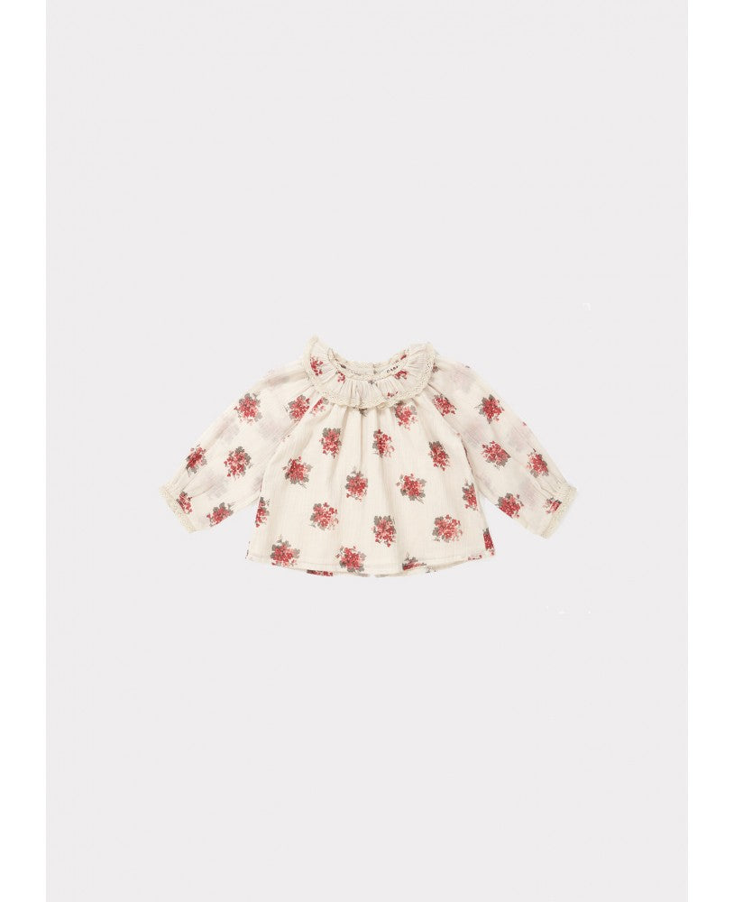 blusa bebé, padrão floral rosa \ encarnado em fundo bege, volumosa com um colarinho plissado largo, mangas compridas com renda nos punhos, pregas na frente e nas costas, botões nas costas 