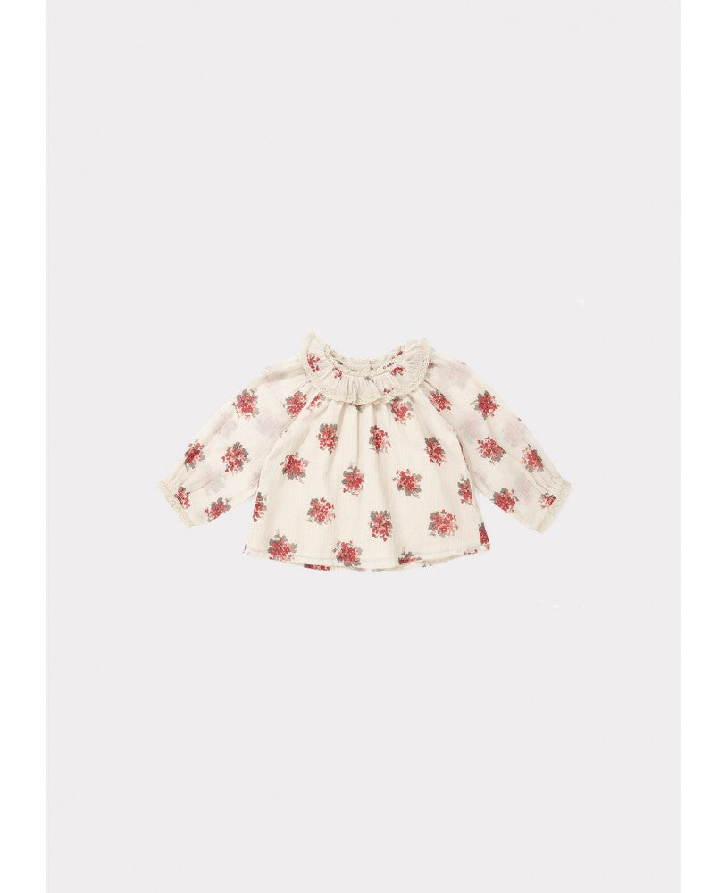 blusa bebé, padrão floral rosa \ encarnado em fundo bege, volumosa com um colarinho plissado largo, mangas compridas com renda nos punhos, pregas na frente e nas costas, botões nas costas