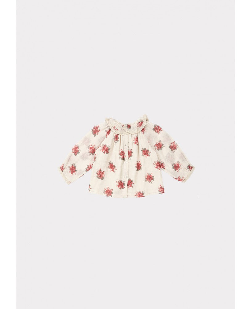 blusa bebé, padrão floral rosa \ encarnado em fundo bege, volumosa com um colarinho plissado largo, mangas compridas com renda nos punhos, pregas na frente e nas costas, botões nas costas