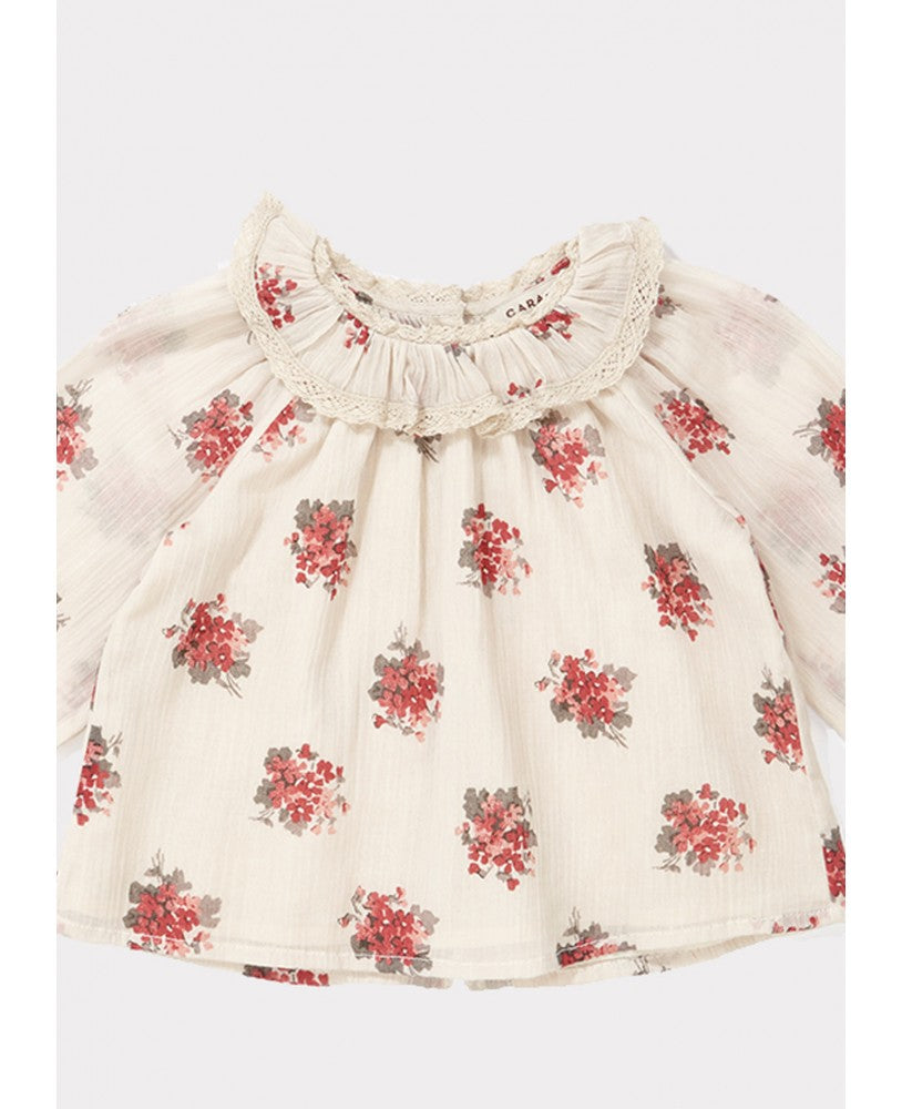 blusa bebé, padrão floral rosa \ encarnado em fundo bege, volumosa com um colarinho plissado largo, mangas compridas com renda nos punhos, pregas na frente e nas costas, botões nas costas