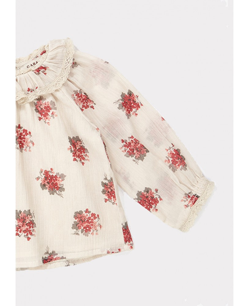 blusa bebé, padrão floral rosa \ encarnado em fundo bege, volumosa com um colarinho plissado largo, mangas compridas com renda nos punhos, pregas na frente e nas costas, botões nas costas