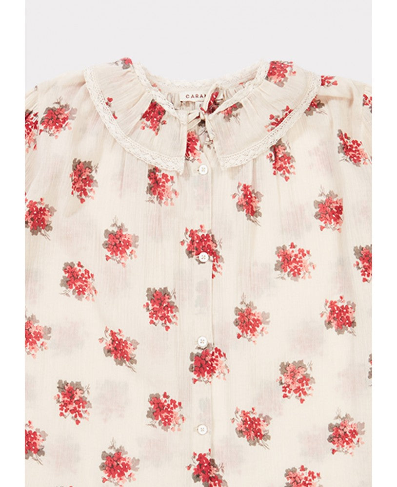 pormenor gola,camisa padrão floral rosa \ encarnado em fundo bege, volumosa com um colarinho plissado largo, mangas compridas com renda nos punhos, pregas na frente e nas costas
