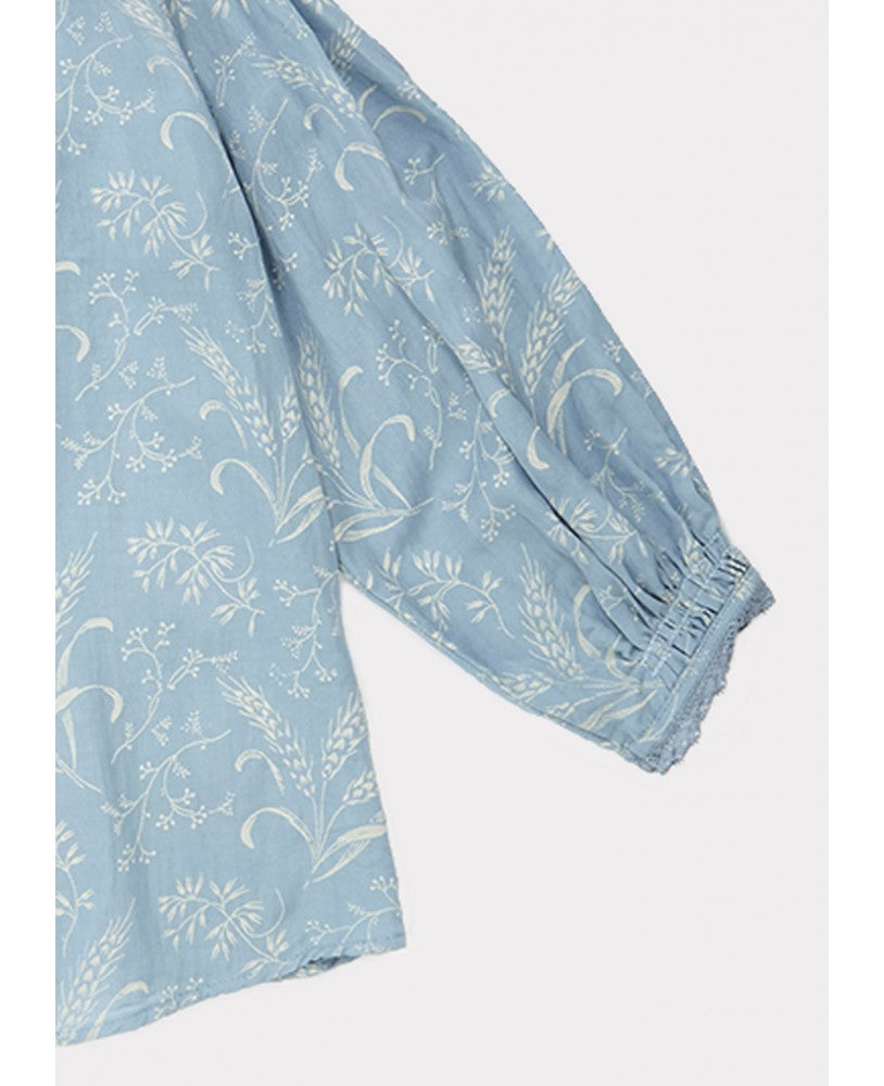 pormenor mangas,camisa azul com padrão bege campestre, volumosa com um colarinho plissado largo, mangas compridas com renda nos punhos, pregas na frente e nas costas